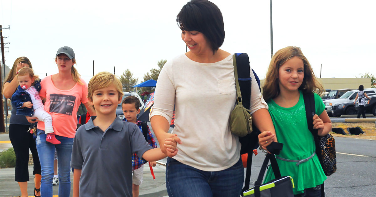 adult with children holding hands and crossing the street