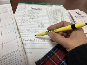 hand with pen and handwritten budgeting figures