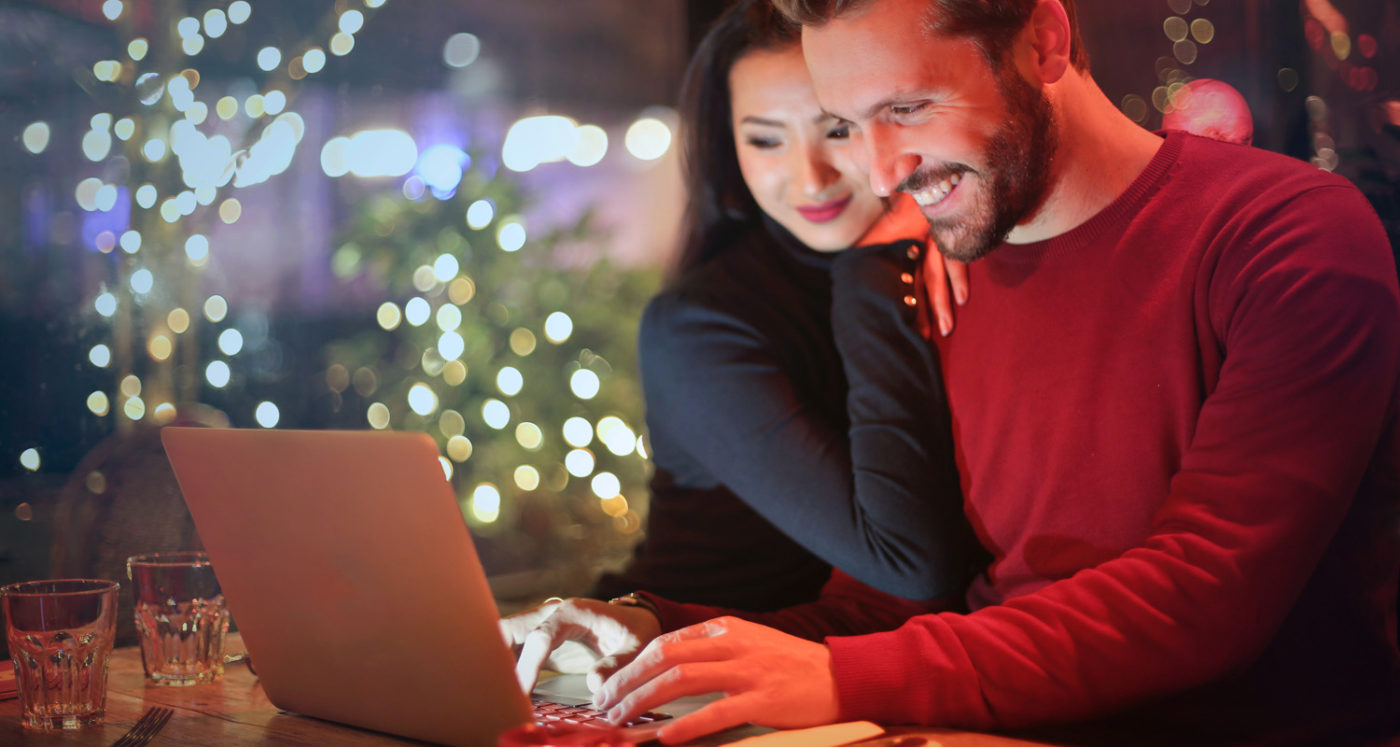 couple using a computer with holiday lights in background